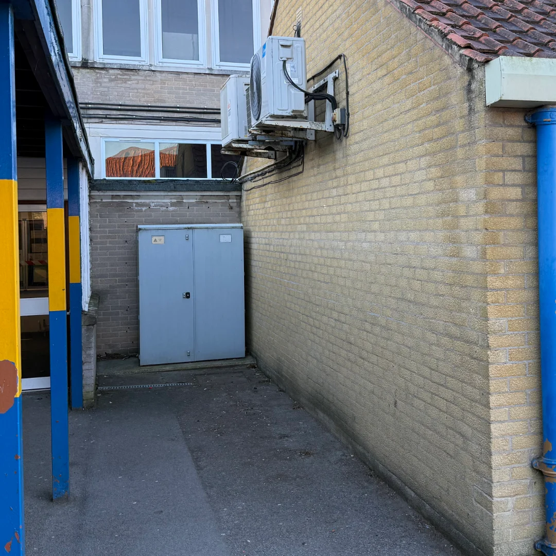 The side of a school building in a yellow brick construction, before a bespoke bag storage unit was installed.