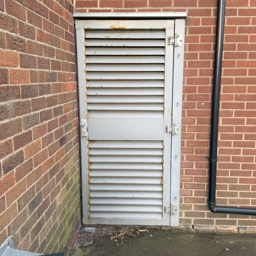 A tired looking off white slatted door before being replaced.