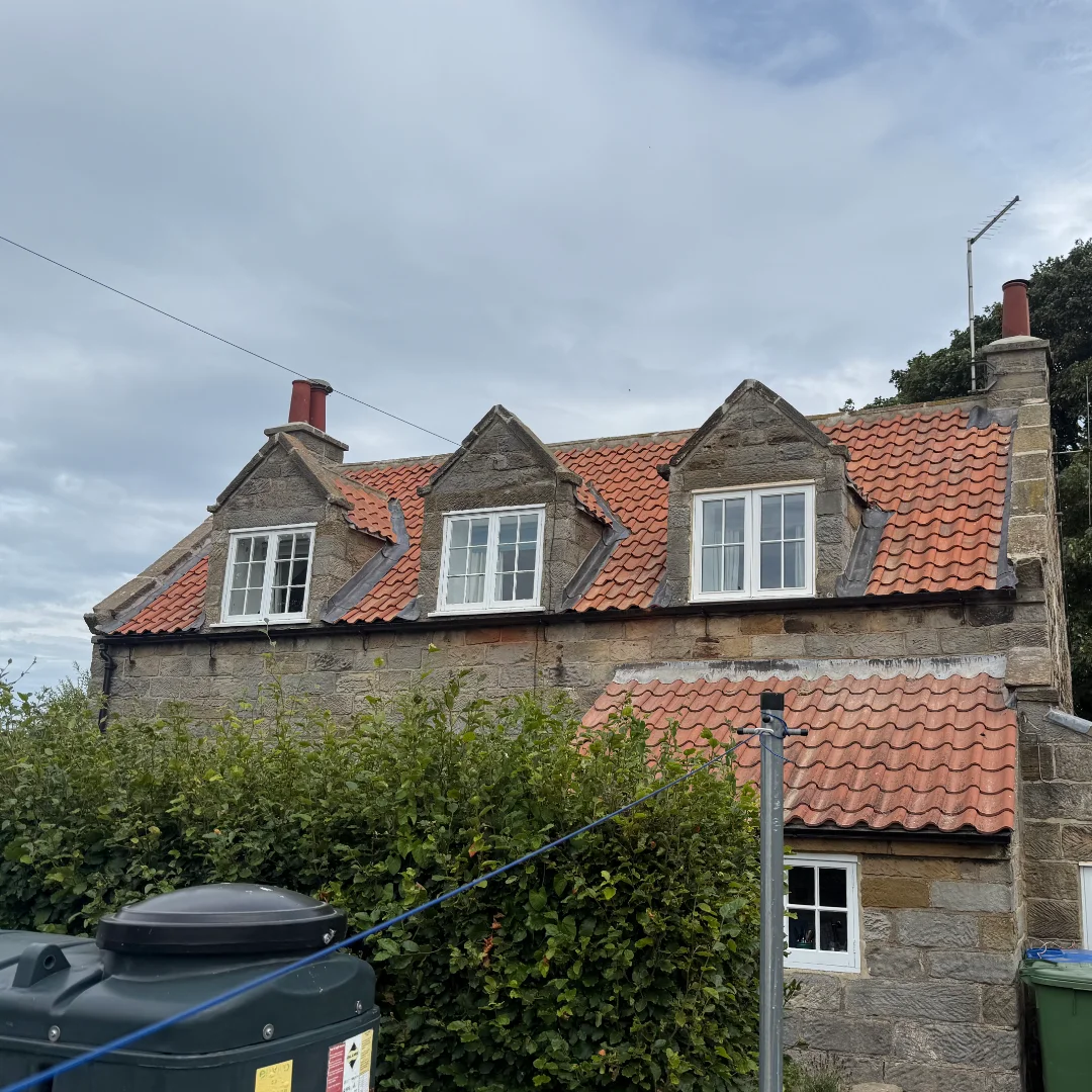 A rear of a traditional cottage with a newly replaced red tiled roof.