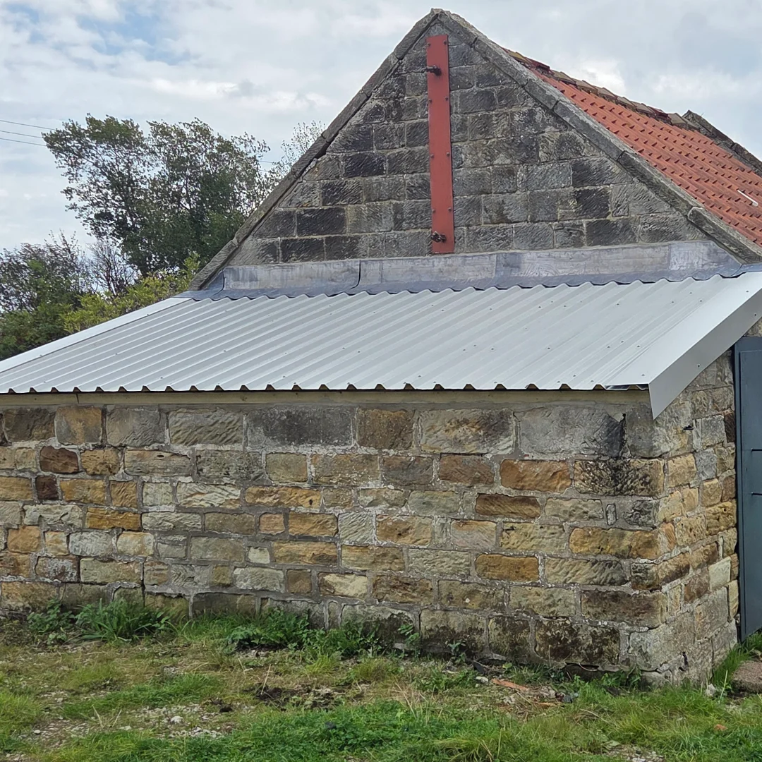A stone-built lean-to stable with a clean, modern corrugated roof.
