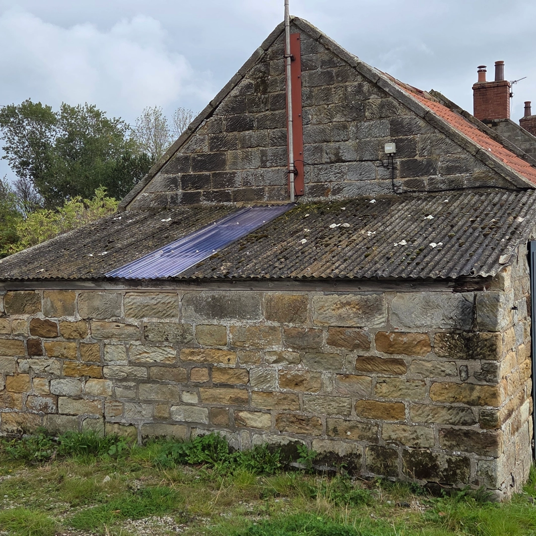 A stone-built lean-to stable with a dirty old asbestos roof.